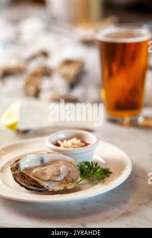 Huître sur une demi coquille avec sauce cocktail et bière verticale Banque D'Images