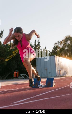 Athlète féminine sprintant hors de blocs Banque D'Images