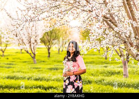 Femme souriante tenant des fleurs d'amande au printemps Banque D'Images