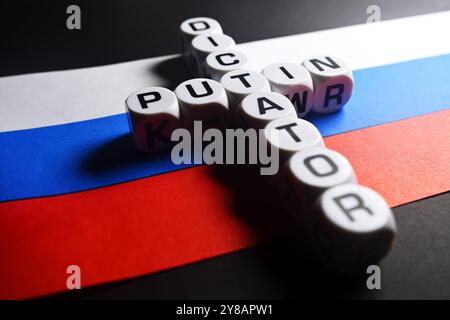 Les cubes de lettres forment les mots Poutine et dictateur en forme de croix sur le drapeau russe, Buchstabenwürfel formen die Wörter Poutine und dictateur (engl.) A Kreuzf Banque D'Images