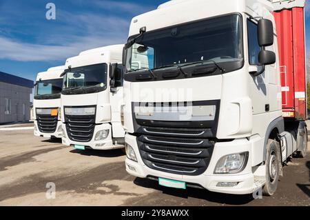 trois camions stationnés les uns à côté des autres dans un parking par une journée ensoleillée. vue des cabines blanches des tracteurs-remorques. Véhicules utilitaires, publicité o Banque D'Images