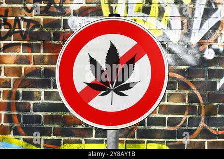 MONTAGE PHOTO, panneau avec feuille de cannabis barrée devant un mur, interdiction de cannabis, FOTOMONTAGE, Schild mit durchgestrichenem Cannabisblatt vor einer Banque D'Images