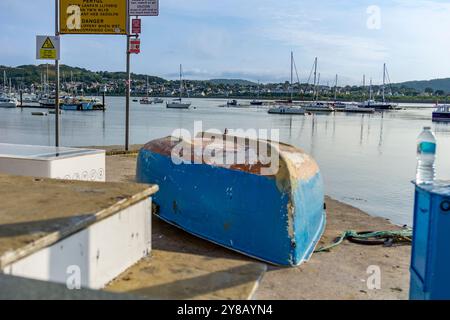 Canot renversé sur l'embarcadère avec vue sur les bateaux amarrés et Deganwy sur la rivière Conwy, au pays de Galles. Banque D'Images