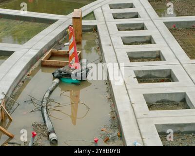 En construction projet de construction inachevé avec béton et bois. Cônes orange et tuyau au sol. Design carré en béton d'architecture Banque D'Images