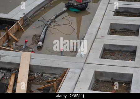 En construction projet de construction inachevé avec béton et bois. Cônes orange et tuyau au sol. Design carré en béton d'architecture Banque D'Images