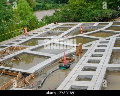 En construction projet de construction inachevé avec béton et bois. Cônes orange et tuyau au sol. Design carré en béton d'architecture Banque D'Images