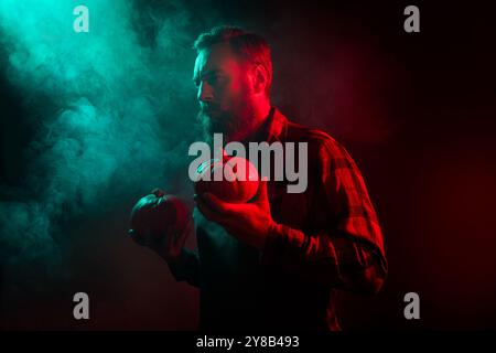 Photo de l'homme du diable avec la citrouille d'halloween célébrer la nuit isolée sur fond sombre brumeux mystérieux Banque D'Images