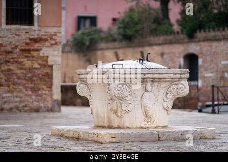 Vieux puits d'eau à Venise, Italie. Gros plan d'un ancien puits en marbre pour l'eau de pluie, Campo S. Marziale, Venise. Banque D'Images