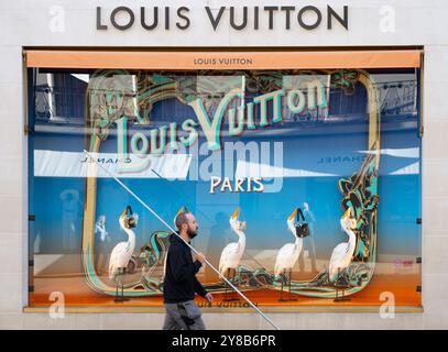 New Bond Street, Londres, Royaume-Uni. 4 octobre 2024. Matinée ensoleillée dans la rue commerçante de luxe de Londres après plusieurs jours de bruine et de ciel gris. Un homme au long perche passe devant la fenêtre de style parisien de Louis Vuitton. Crédit : Malcolm Park/Alamy Live News Banque D'Images