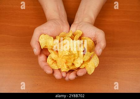 Calories. Obésité. Cuisine américaine. Restauration rapide. Malbouffe. Mode de vie malsain. Homme mangeant des chips. Tient les croustilles à la main. Une vue d'une main Banque D'Images