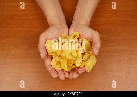 Calories. Obésité. Cuisine américaine. Restauration rapide. Malbouffe. Mode de vie malsain. Homme mangeant des chips. Tient les croustilles à la main. Une vue d'une main Banque D'Images