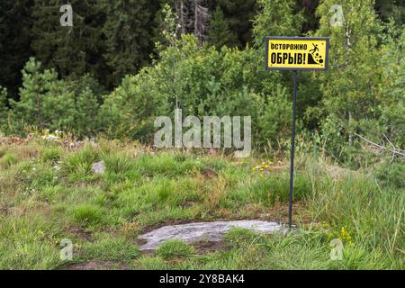 Panneau d'avertissement jaune monté au sommet du mont Paasonvuori, Sortavala, Russie. Texte russe signifie : méfiez-vous de la falaise! Banque D'Images