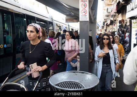 Jérusalem, Israël - 1er octobre 2024, arrêt de tramway près du marché Mahane Yehuda. Différents groupes de personnes, des orthodoxes aux laïcs, s'éloignent de th Banque D'Images