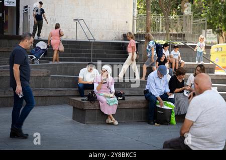 Jérusalem, Israël - 1er octobre 2024, les gens se reposent, assis sur des marches de pierre et des bancs dans le centre-ville. Orthodoxe et laïque, les femmes et m Banque D'Images