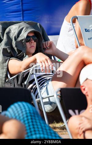 VESTE AU-DESSUS DE LA TÊTE, FANS EN TRANSATS, BEACH VOLLEY, MARIEHAMN, 2011 : une femme s'imprégne du sport protégé du soleil avec une veste au-dessus de la tête. Les gens regardent l'action de volley-ball de plage dans des transats relaxants sur les courts extérieurs en vêtements d'été ou en vêtements de plage lors d'une journée d'été exceptionnellement chaude de la mer Baltique en août 2011 au PAF Open à Mariehamn, Åland, Finlande. Photographie : Rob Watkins. INFO : entre 2009-2013, le tournoi PAF Open Beach Volleyball était un événement annuel organisé à Mariehamn, Åland, Finlande. Il a attiré les meilleures équipes et joueurs internationaux comme partie de classement de l'offi Banque D'Images