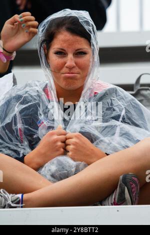 HUMOUR SOUS LA PLUIE, TEMPÊTE ESTIVALE, BEACH VOLLEY, MARIEHAMN, 2011 : une jeune femme voit le côté drôle des choses. La foule se couvre avec des ponchos jetables alors qu'une énorme tempête estivale balaye le stade avec un déluge de pluie pendant les demi-finales en août 2011 au PAF Open à Mariehamn, Åland, Finlande. Photographie : Rob Watkins. INFO : entre 2009-2013, le tournoi PAF Open Beach Volleyball était un événement annuel organisé à Mariehamn, Åland, Finlande. Il a attiré les meilleures équipes et joueurs internationaux en tant que partie du classement officiel du circuit mondial FIVB, mettant en vedette le vol de plage de haut niveau Banque D'Images