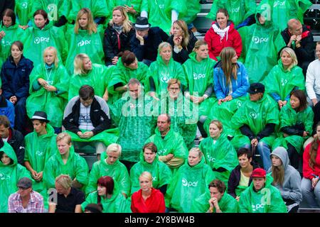 TEMPÊTE ESTIVALE, BEACH VOLLEY, MARIEHAMN, 2011 : tirer le meilleur parti des choses. La foule se couvre avec des ponchos jetables alors qu'une énorme tempête estivale balaye le stade avec un déluge de pluie pendant les demi-finales en août 2011 au PAF Open à Mariehamn, Åland, Finlande. Photographie : Rob Watkins. INFO : entre 2009-2013, le tournoi PAF Open Beach Volleyball était un événement annuel organisé à Mariehamn, Åland, Finlande. Il a attiré les meilleures équipes et joueurs internationaux dans le cadre du circuit mondial officiel de la FIVB, mettant en vedette le Beach volley de haut niveau. Banque D'Images