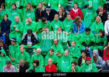 TEMPÊTE ESTIVALE, BEACH VOLLEY, MARIEHAMN, 2011 : tirer le meilleur parti des choses. La foule se couvre avec des ponchos jetables alors qu'une énorme tempête estivale balaye le stade avec un déluge de pluie pendant les demi-finales en août 2011 au PAF Open à Mariehamn, Åland, Finlande. Photographie : Rob Watkins. INFO : entre 2009-2013, le tournoi PAF Open Beach Volleyball était un événement annuel organisé à Mariehamn, Åland, Finlande. Il a attiré les meilleures équipes et joueurs internationaux dans le cadre du circuit mondial officiel de la FIVB, mettant en vedette le Beach volley de haut niveau. Banque D'Images