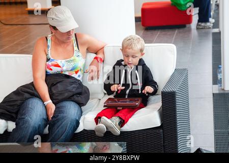 TEMPÊTE ESTIVALE, BEACH VOLLEY, MARIEHAMN, 2011 : un muim ether fils s'abritent à l'intérieur avec un iPad alors qu'une énorme tempête estivale balaye le stade avec un déluge de pluie pendant les demi-finales en août 2011 à l'Open de la PAF à Mariehamn, Åland, Finlande. Photographie : Rob Watkins. INFO : entre 2009-2013, le tournoi PAF Open Beach Volleyball était un événement annuel organisé à Mariehamn, Åland, Finlande. Il a attiré les meilleures équipes et joueurs internationaux dans le cadre du circuit mondial officiel de la FIVB, mettant en vedette le Beach volley de haut niveau. Banque D'Images