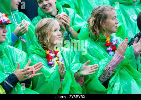 HAWAÏENS LEIS, TEMPÊTE ESTIVALE, BEACH VOLLEY, MARIEHAMN, 2011 : les fans aux cheveux mouillés essaient de tirer le meilleur parti des choses en portant des Leis hawaïens par-dessus leurs imperméables. La foule se couvre avec des ponchos jetables alors qu'une énorme tempête estivale balaye le stade avec un déluge de pluie pendant les demi-finales en août 2011 au PAF Open à Mariehamn, Åland, Finlande. Photographie : Rob Watkins. INFO : entre 2009-2013, le tournoi PAF Open Beach Volleyball était un événement annuel organisé à Mariehamn, Åland, Finlande. Il a attiré les meilleures équipes et joueurs internationaux comme une partie de classement de la of Banque D'Images