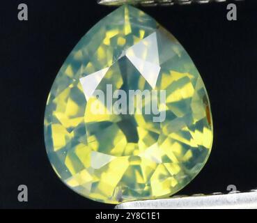 Pierre précieuse saphir jaune rayonnant gracieusement capturée en gros plan, mettant en valeur ses facettes fascinantes et sa brillance lumineuse. Banque D'Images