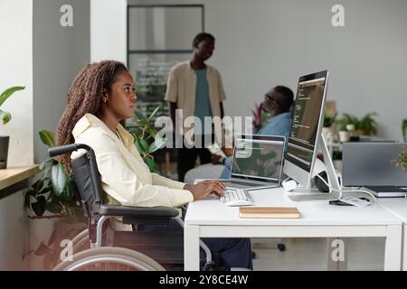 Vue de côté d'un travailleur afro-américain avec un programme de handicap dans un bureau moderne Banque D'Images