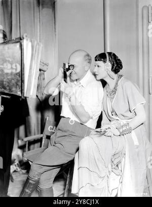 Le réalisateur CECIL B. DeMille et CLAUDETTE COLBERT sur le plateau film de contrôle franc lors du tournage de CLÉOPÂTRE 1934 le réalisateur CECIL B. DeMille costumes de Miss Colbert Travis Banton Paramount Pictures Banque D'Images