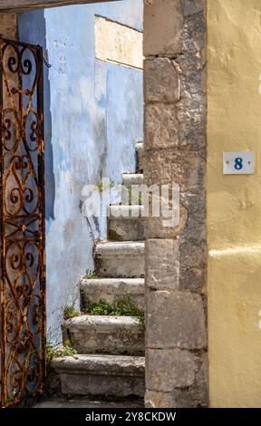 escalier en pierre partiellement obscurci ou escalier de marches en pierre derrière la porte laissée entrouverte sur un vieux bâtiment abandonné donnant un sentiment de mystère ou d'atmosphère. Banque D'Images