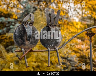 Décoration de jardin en métal de deux figures abstraites d'oiseaux perchées sur une branche Banque D'Images