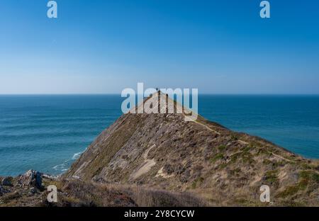 Randonneur debout au sommet de la falaise à la pointe Sharpnose plus élevée sur le South West Coast Path et profitant de la vue imprenable Banque D'Images