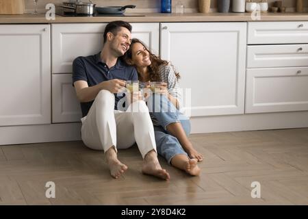 Couple marié rêveur positif reposant sur le sol chaud Banque D'Images