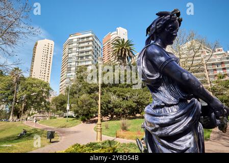 Sculpture grecque antique de femme tenant une amphore. Cette statue est située dans un grand parc avec des monticules et des tuiles rouges coloniales décorant le sinueux A. Banque D'Images