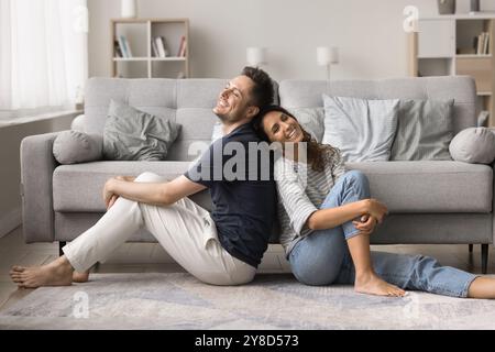 Heureux couple détendu assis dos à dos sur moquette Banque D'Images