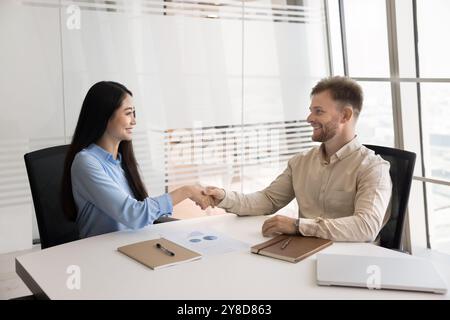 Heureux entrepreneurs multiethniques prospères se serrant la main à la réunion Banque D'Images