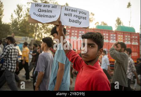 Un garçon musulman chiite du Cachemire tient une pancarte qui dit : « nous sommes tous Qasim Soleimani, et Israël, vous le regretterez » lors d'une marche de protestation. Les musulmans chiites ont organisé un rassemblement de protestation condamnant les actions militaires israéliennes en cours au Liban et en Palestine, ainsi que l'assassinat de Sayyed Hassan Nasrallah, dirigeant de longue date du Hezbollah. Nasrallah a été tué dans une frappe aérienne israélienne le 27 septembre 2024 à Beyrouth, qui a visé le siège central du Hezbollah dans un contexte de tensions croissantes entre Israël et le Hezbollah. La frappe aérienne a également entraîné la mort de plusieurs hauts commandants du Hezbollah, i. Banque D'Images