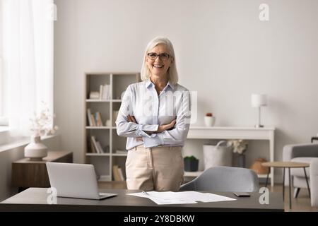 Femme d'affaires confiante dans une tenue d'affaires élégante posant au lieu de travail moderne Banque D'Images