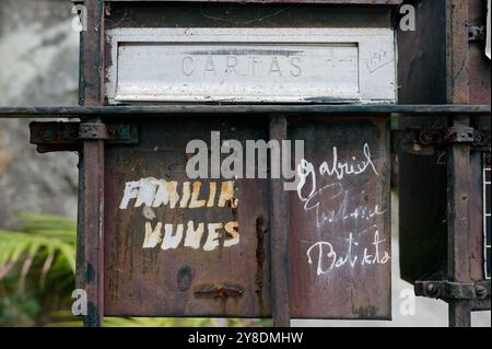 Boîte aux lettres familiale rouillée et altérée avec noms manuscrits Banque D'Images