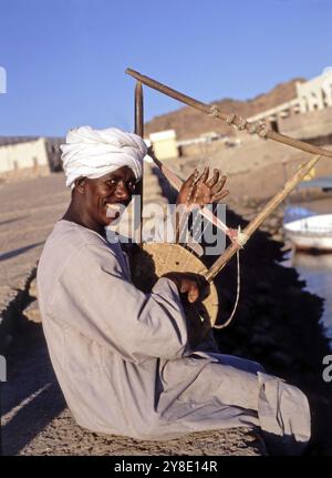 Musicien à Assouan jouant un instrument à cordes fait maison Banque D'Images