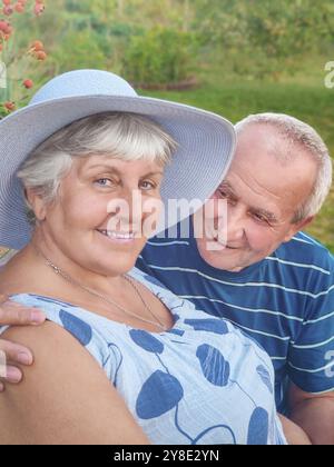 Photo authentique en plein air d'un couple vieillissant s'amusant dans le jardin et béni avec amour. Au cours de leur jeu, l'homme essaie d'embrasser son partenaire et elle l'est Banque D'Images