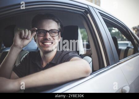 Profitez de la conduite. Image d'un jeune beau gars assis dans la voiture Banque D'Images