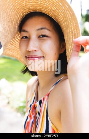 Portrait de femme asiatique heureuse avec les cheveux courts portant chapeau de soleil dans le jardin à la maison Banque D'Images