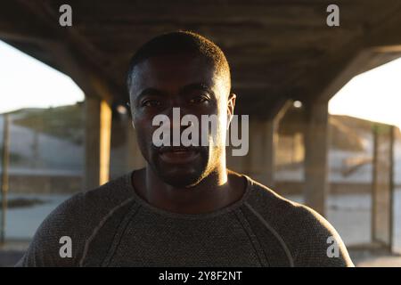 Portrait d'homme afro-américain exerçant à l'extérieur sur le pont au coucher du soleil Banque D'Images