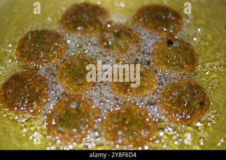 Frire des boules de falafel traditionnelles égyptiennes frites dans de l'huile profonde, burger vert, à base de pois chiches moulus et de fèves, boules frites ou en forme de galette Banque D'Images