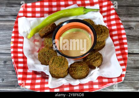 Boules de falafel traditionnelles égyptiennes frites avec Tahini et poivron vert servies dans une assiette, burger vert, à base de pois chiches moulus et de fèves, en profondeur Banque D'Images