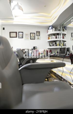 Vue rapprochée de l'intérieur du salon de coiffure avec chaises et certificats encadrés sur le mur. Banque D'Images