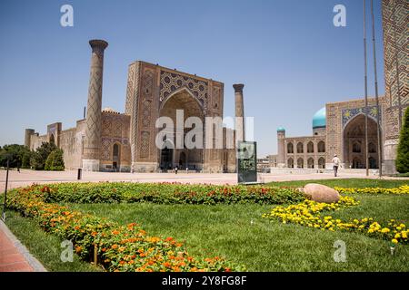 Samarcande, Ouzbékistan - 05 juillet 2024 : portail et colonnes à Ulug Beg madrassa dans le Registan de Samarcande avec jardin de fleurs partie supérieure du Regis Banque D'Images