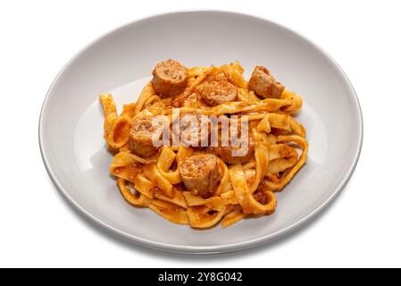 Tagliatelle pâtes aux œufs avec sauce tomate rouge avec morceaux de saucisse dans une assiette blanche isolée sur blanc avec chemin de coupe inclus Banque D'Images