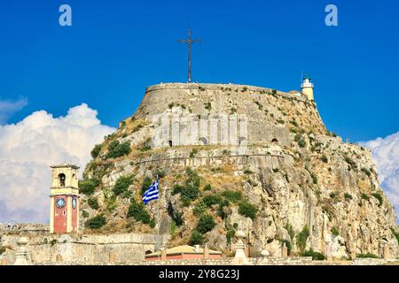 Corfou, Grèce - 4 septembre 2024 : ancienne forteresse de Corfou avec un clocher frappant encastré dans les rochers et une grande croix dressée sur le point culminant de la forteresse *** Alte Festung von Korfu mit einem markanten Glockenturm, der in die Felsen eingebettet ist, und einem großen Kreuz, das auf dem höchsten Punkt der Festung steht Banque D'Images