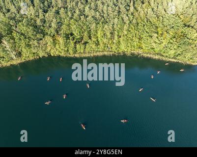 Vue aérienne par drone de personnes faisant du kayak sur un lac entouré d'une forêt verdoyante. Voile en kayaks rouges dans la région des lacs de Masurian. Lac Lesk dans la Kulka Banque D'Images