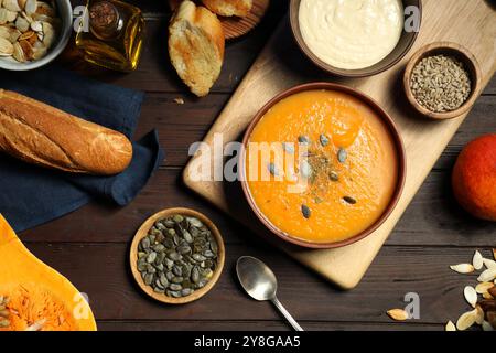 Délicieuse soupe de citrouille, épices et produits sur table en bois, plat Banque D'Images